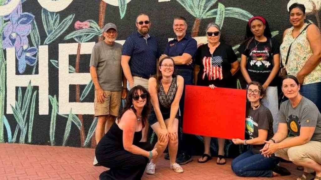 Fate Community Theatre's founding members pose together in front of a painted mural in Fate, Texas